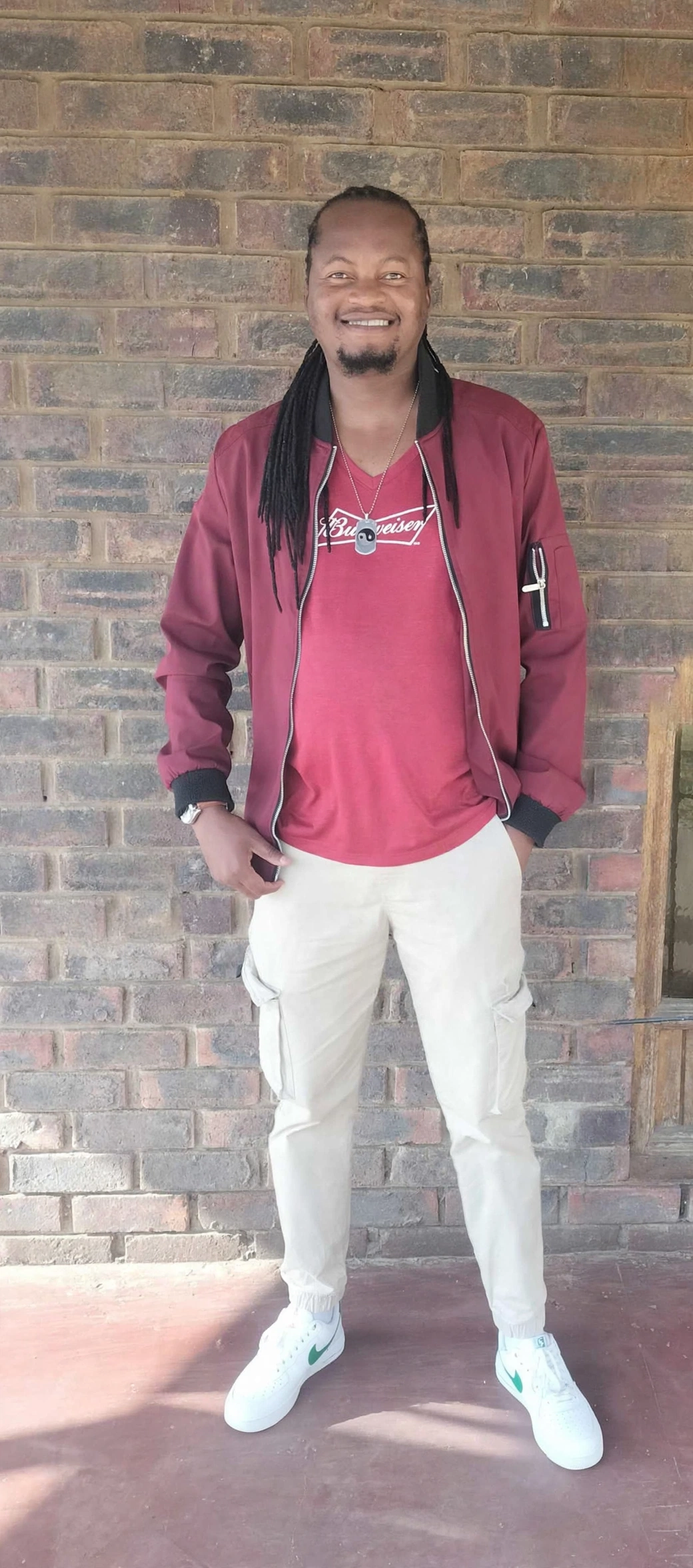 Masapo offstage in a maroon jacket against a brick wall